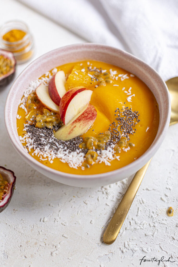sonnige gelbe Smoothie-Bowl in der Geschmacksrichtung Mango-Orange-Karotte-Kurkuma mit Kokosraspeln und Chiasamen, Rezept